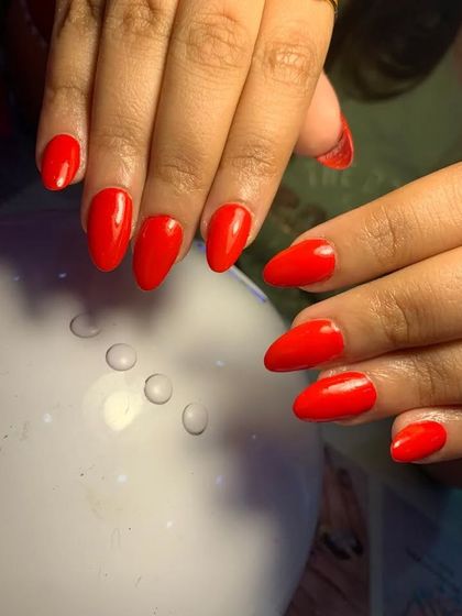 A classic and bold set of solid bright red nails on an almond shape.