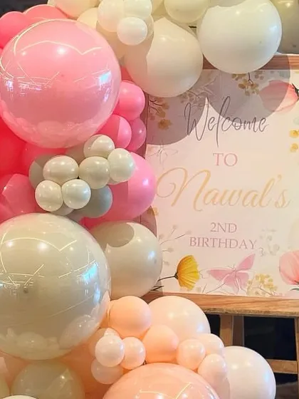 A beautiful welcome sign for a second birthday, nestled in a stunning organic balloon garland of pink, peach, and white. Butterfly details add a touch of whimsy.