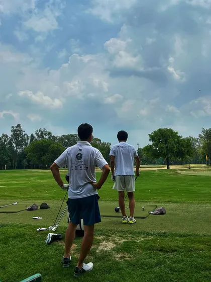 Two golfers stand on the tee box, contemplating their next shot under a cloudy sky.