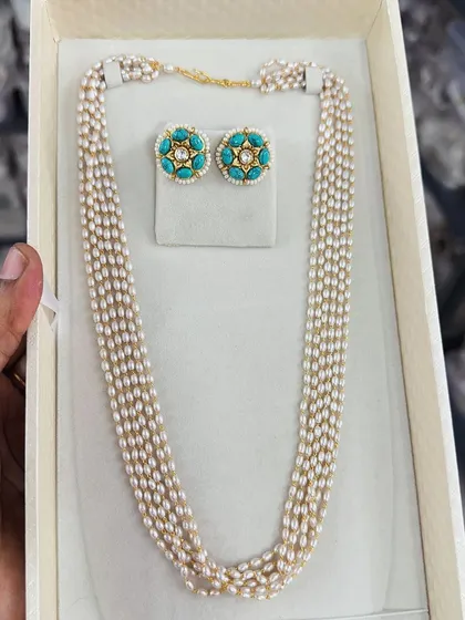 A simple and elegant multi-strand pearl necklace paired with turquoise-colored studs. This set is perfect for adding a touch of class to both modern and traditional outfits.