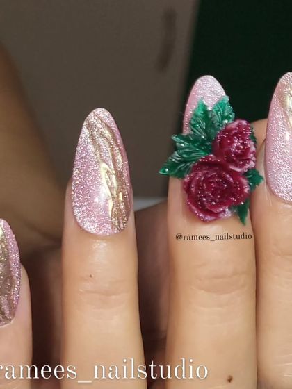 A stunning set of press-on nails featuring a sparkling pink cat-eye base. The accent nail is adorned with a beautiful bouquet of hand-sculpted deep red roses.