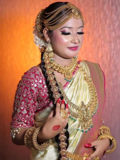A model showcasing a unique South Indian bridal look with a side-swept hair braid adorned with heavy gold-plated jewellery.