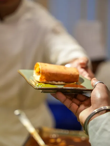 A perfectly rolled dosa, fresh off the tawa, being served to a guest. This is how we deliver authentic taste with impeccable service.