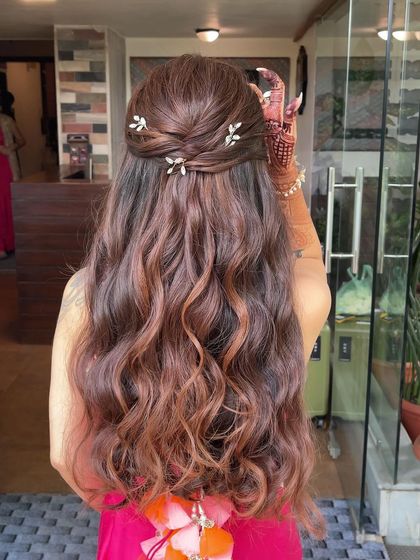 A half up, half down hairstyle perfect for a Mehndi ceremony. The hair is twisted back and adorned with small, delicate leaf pins.