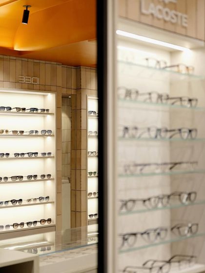 A mirror reflects the store's interior, showcasing the depth and cohesive design created by the repetition of materials and lighting.