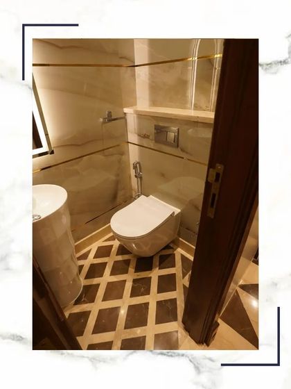 This compact bathroom uses smart design to feel spacious and luxurious. It features a pedestal sink, a wall-mounted commode, and beautiful diamond-patterned floor tiles.