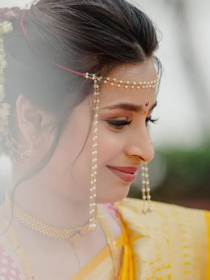 A close-up profile of a Maharashtrian queen in her Paithani. The delicate 'mundavalya' and soft makeup create a look of ethereal beauty.