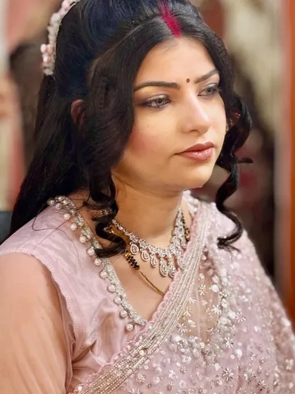 A soft and subtle party makeup look. The focus is on clean skin and gentle curls, perfect for an engagement or family gathering.