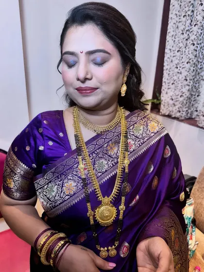 The complete guest makeup look in a traditional purple saree. The eyes are softly smoked, and the skin is given a healthy, luminous finish.