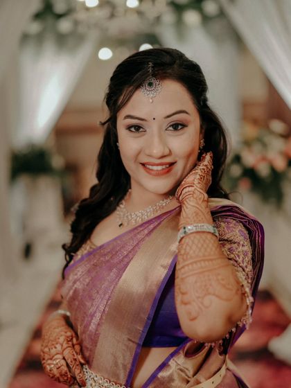 A happy and welcoming portrait of a bride at her reception, with beautiful henna designs on her hands.