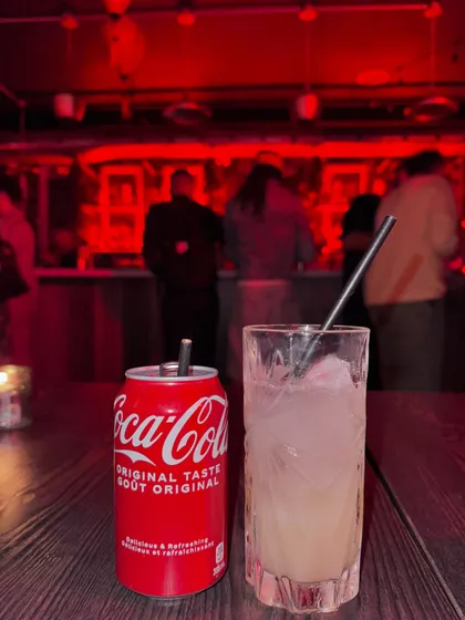 A close-up of drinks at a bar with moody red lighting, setting the scene for a night out.