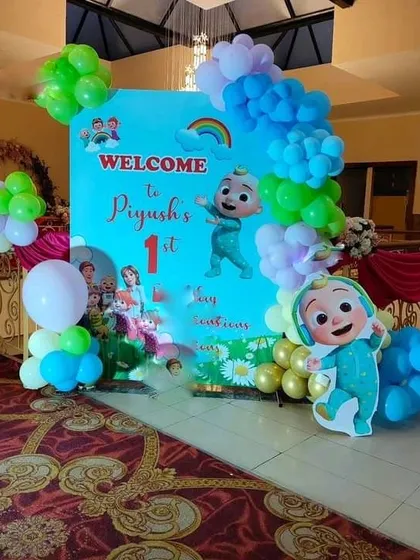 A Cocomelon themed welcome for "Piyush's 1st" birthday. This entrance decoration uses a custom backdrop with characters and a colorful balloon arrangement.