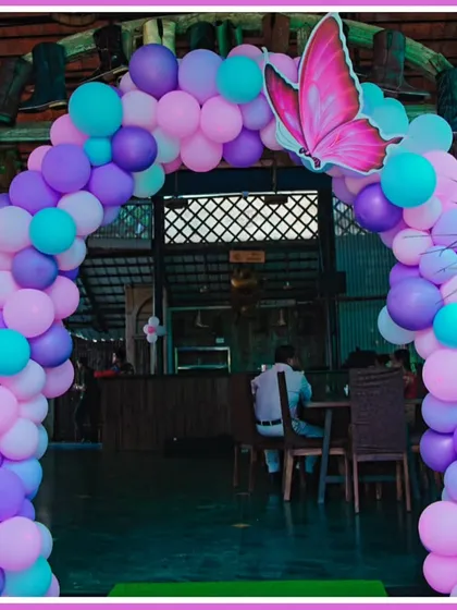 A welcoming balloon arch for a butterfly-themed party, in shades of purple, pink, and teal.