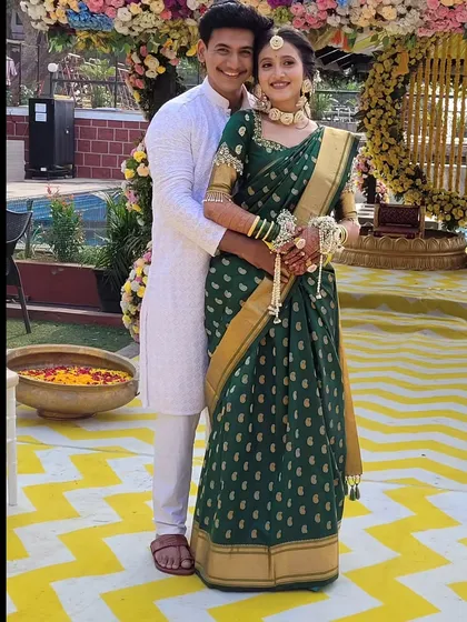 A happy couple at their Haldi ceremony, with the bride wearing a green saree I draped into a lehenga. This style is both traditional in fabric and modern in form.