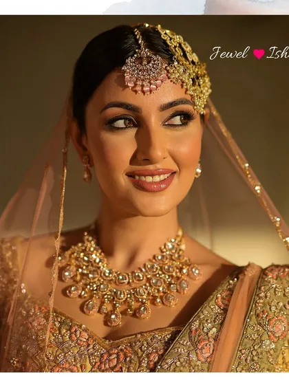 A radiant bridal portrait. The soft lighting enhances the glow of the uncut Polki necklace and the intricate embroidery of her outfit.