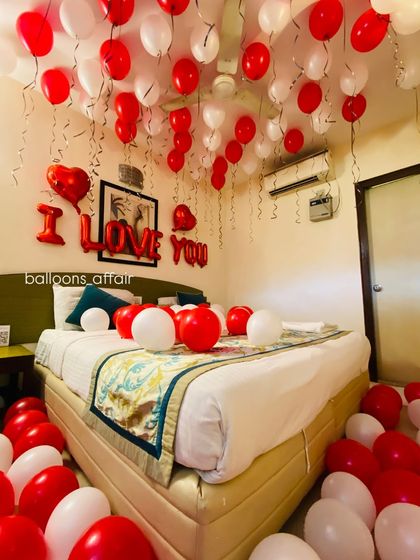 A close-up on the bed, showing the mix of red and white balloons and the clear "I LOVE YOU" banner, perfect for a romantic gesture.
