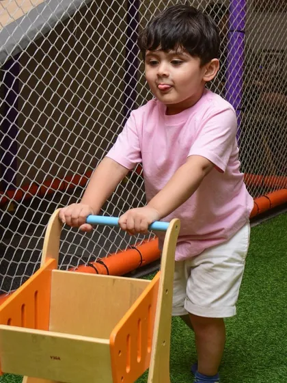 Let's go shopping! A little one pushing a wooden cart through our play area.
