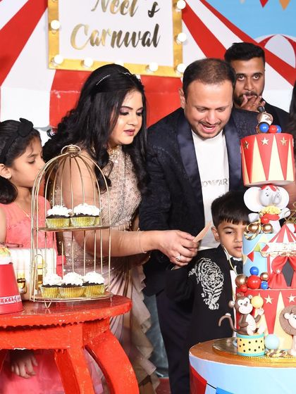 The cake-cutting moment at Neel's carnival party, with the family gathered around the amazing circus cake.