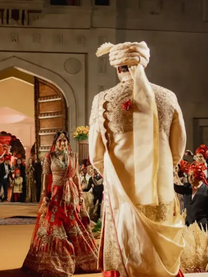 The first look. This powerful moment is framed by the aisle, lined with pampas grass and florals, leading to the grand fort-style entrance. I design the entire processional to feel like a story unfolding.