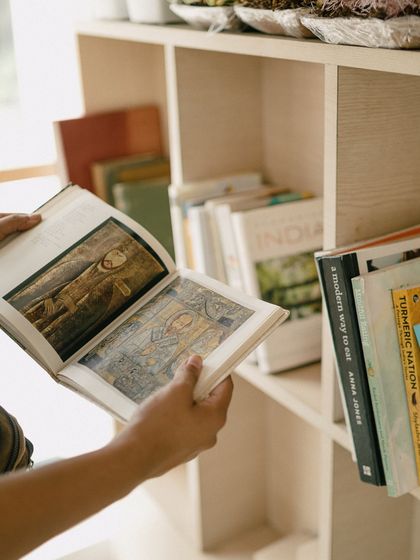 Flipping through a book filled with beautiful art. Our collection isn't just for reading; it's full of visual inspiration, perfect for browsing on a lazy afternoon.