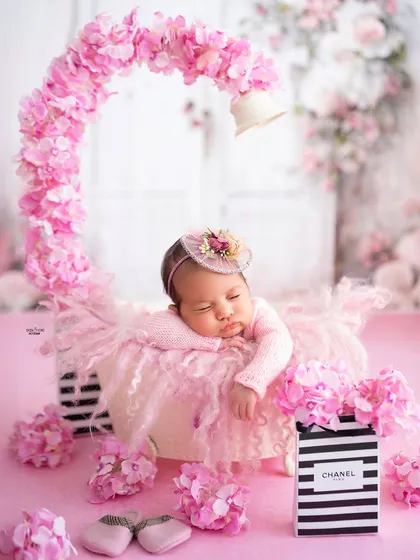 A floral fantasy for a beautiful baby girl. The arch of pink flowers creates a stunning frame for this sleeping newborn portrait.