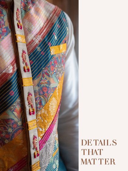 Details that matter. A close-up of the groom's vibrant Nehru jacket, featuring intricate patches and embroidery that add a unique, personal touch to his Sangeet look.