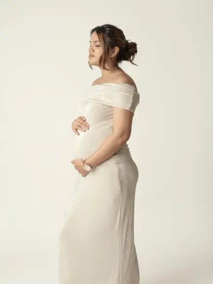 A quiet, contemplative side profile in a beautiful off shoulder gown. This pose is perfect for elegantly showcasing the baby bump and capturing a moment of inner peace.