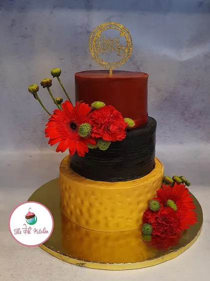 This three-tiered wedding cake makes a vibrant statement with its bold color blocking in red, black, and textured yellow. Decorated with bright red gerbera daisies, it shows how I can create a large, unconventional cake that reflects a couple's personality.