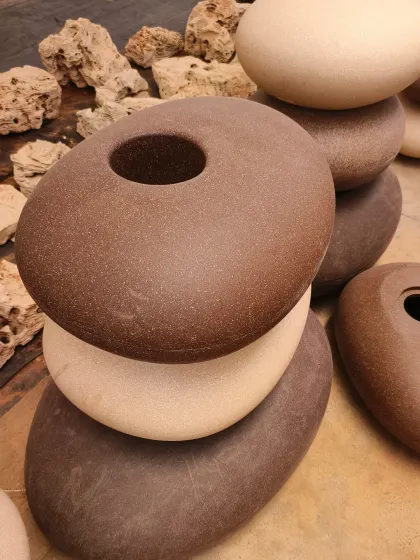A stack of our unique pebble-shaped FRP planters. Available in earthy tones like brown and beige, these are designed for modern gardens and patios.