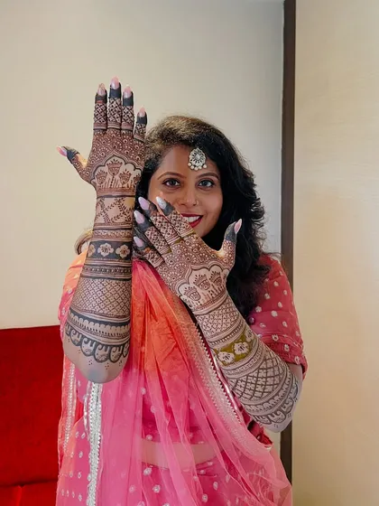 This happy bride is showing off her mehendi, which features adorable elephant figures, a symbol of good luck and prosperity.