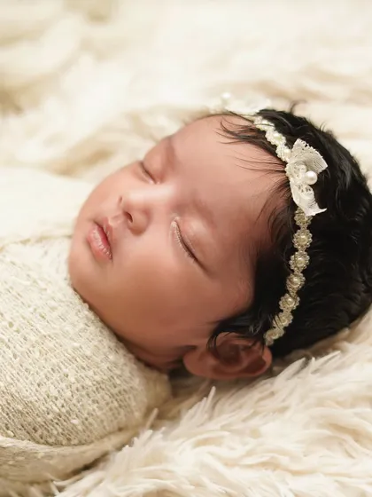 A close-up portrait of the sleeping newborn, focusing on her perfect little face and the details of her headband. These are the quiet moments I love to freeze in time.