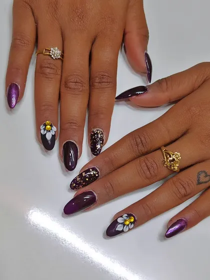 A dark and dramatic set with deep purple nails, accented with glitter and bold 3D flowers.