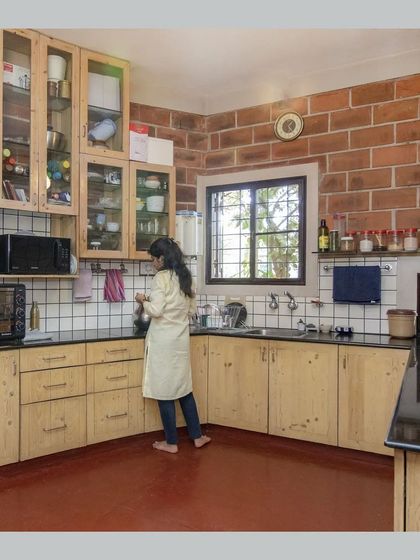 The kitchen, with pine wood cabinets, a black granite countertop, and an exposed brick wall, blending modern functionality with natural aesthetics.