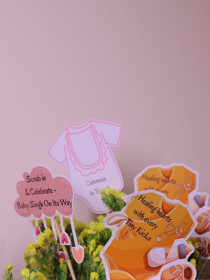 Custom-made decorative picks for the floral arrangements, with cute sayings like "Healing hearts with every tiny kick" and "Scrub in & Celebrate," a nod to the doctor parents-to-be.