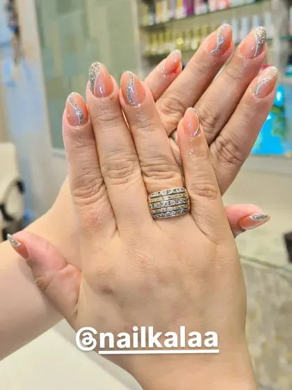 A sophisticated design on almond-shaped nails, featuring a nude base with delicate, wavy silver glitter lines.