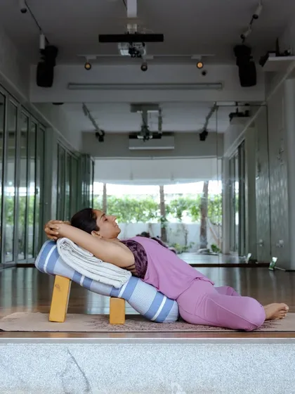 Rest is not a luxury; it's a vital part of our practice. Here, a student finds deep relaxation in Supta Baddha Konasana (Reclining Bound Angle Pose), fully supported by a bolster and bench to open the heart and calm the mind.