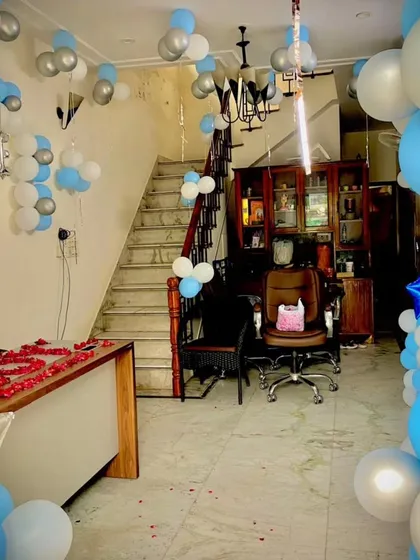 Here is a complete room setup to welcome a baby boy. The decor includes blue and silver "Welcome Baby" balloons, flower-shaped balloon clusters on the walls, and a beautiful arrangement of rose petals on the table.