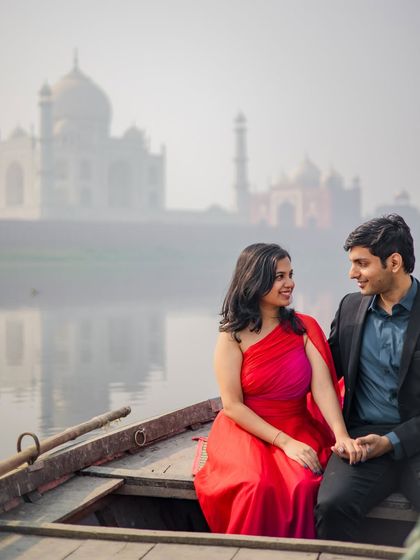 A candid conversation on a boat, with the couple sharing a smile, the Taj Mahal creating a perfect romantic backdrop.