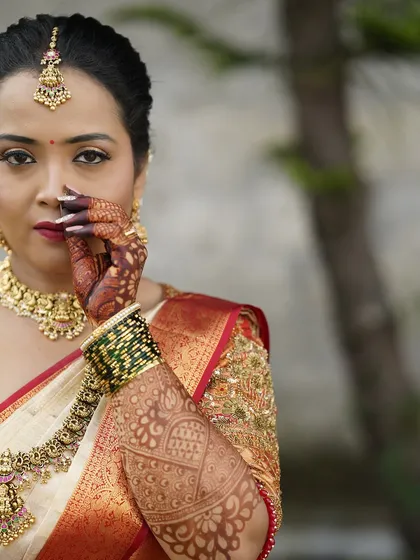 A powerful and confident bridal portrait. This close-up on Samyak showcases the rich red lip, defined eyes, and intricate henna, all key elements of her unforgettable wedding look.