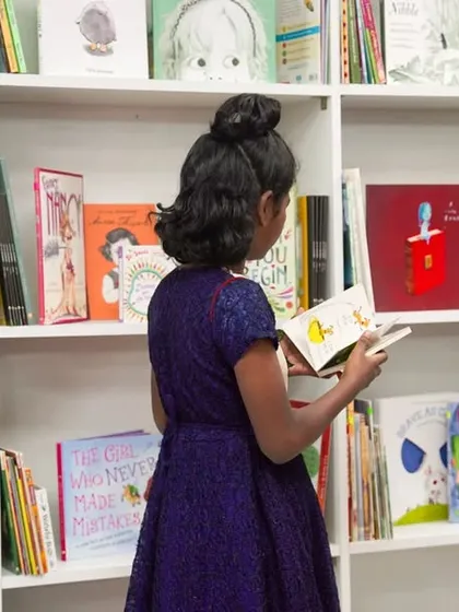A young girl explores the brand-new bookshelves at the "Library of Flowers." For many, this is their first-ever access to a world of stories.