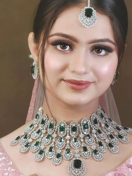 A stunning American Diamond necklace with large green stones. This piece combines the sparkle of diamonds with a pop of traditional color, perfect for a reception.