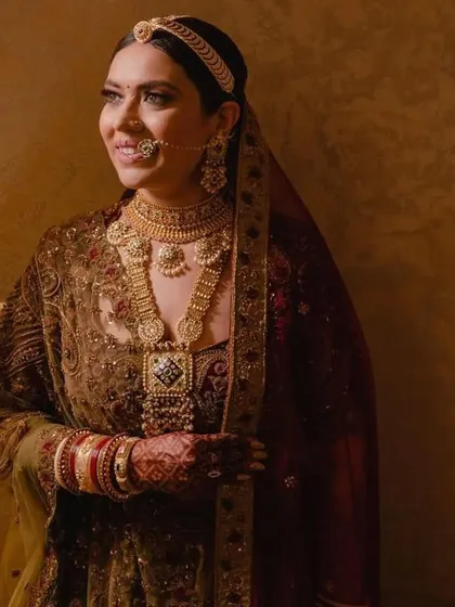 A bride looking serene and beautiful with her hair in a classic floral bun, covered by a dupatta. This is the quintessential traditional bridal look.