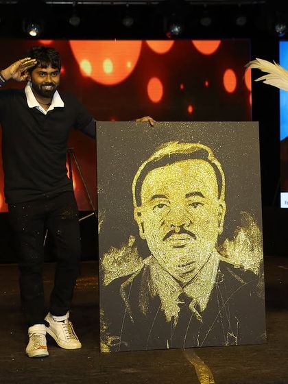 The final reveal of a glitter portrait on a grand stage. The combination of lighting, performance, and the sparkling art creates a memorable spectacle for any large-scale event.