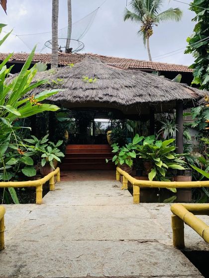 The entrance to one of our dining areas, featuring a thatched roof and surrounded by vibrant green plants. This is the kind of tropical architecture you'll find throughout the resort.