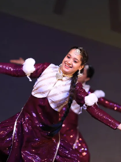 A beautiful close-up of a Bhangra Queens performer, her smile radiating the joy of folk dance on the big stage.