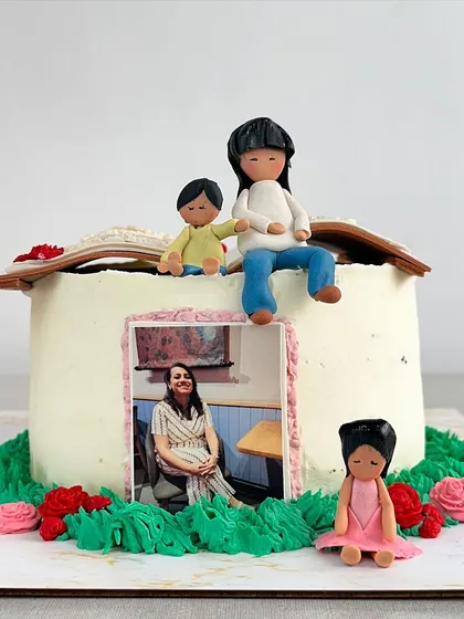 A side view of the storybook cake, showing the edible photo leaning against the side and the small fondant figure of the daughter.