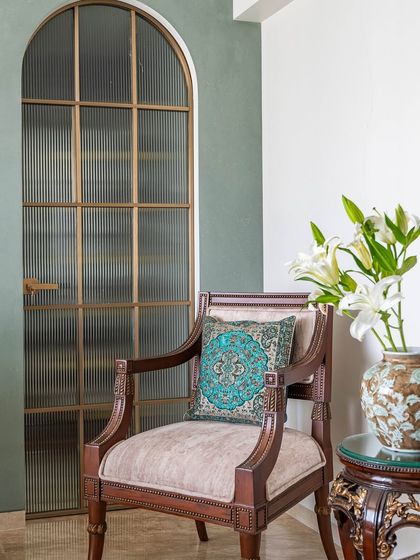 Another view of the 'Eternity' master bedroom, showing the elegant armchair and the arched fluted glass door that separates the sleeping area from the walk-in closet.