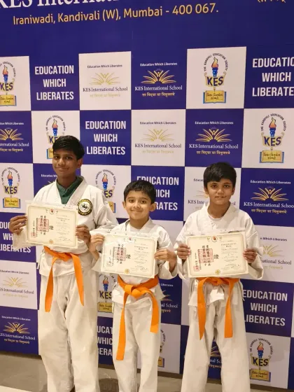 These three students from KES International School have worked hard to earn their orange belts. This intermediate level signifies a stronger grasp of fundamental karate techniques and forms.