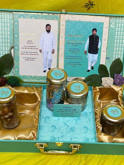 A full view of a light green briefcase-style hamper box. You can see how the space is thoughtfully arranged with compartments for the invitation inserts and multiple jars of sweets and savories.