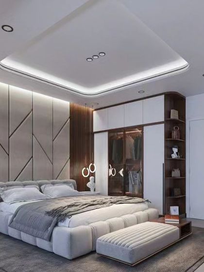 A modern bedroom with a sophisticated grey and wood color scheme. The headboard features geometric upholstered panels, and the integrated wardrobe includes open shelving for display.